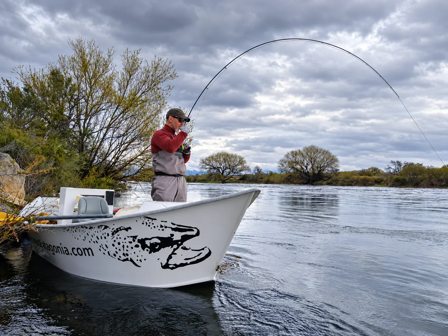 Angler fighting a trout from a drift boat near Bariloche