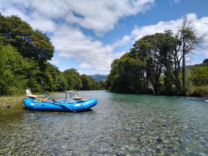 Balsa de pesca en las aguas transparentes del río Manso, rodeado de bosque nativo en Patagonia