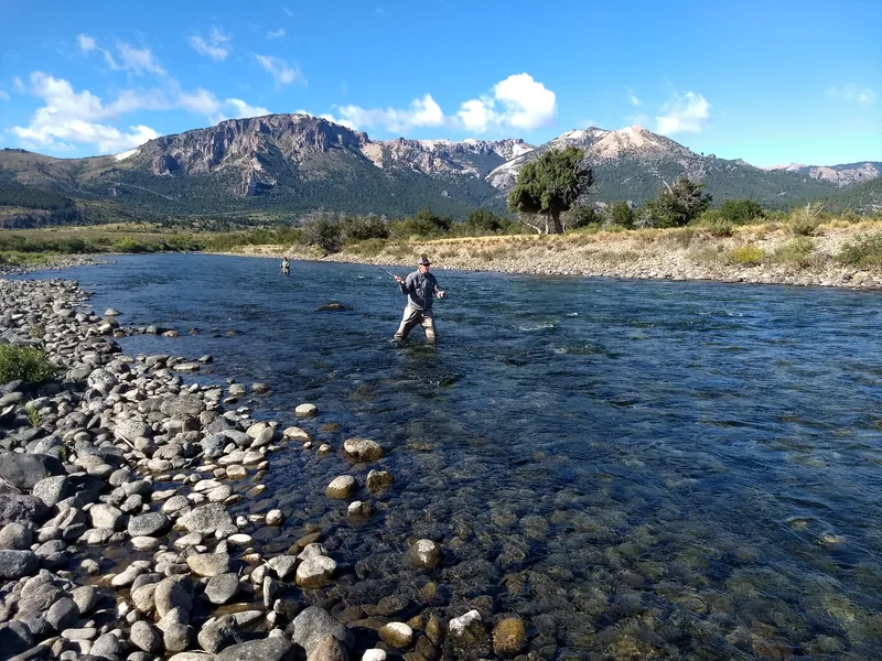 Pescadores con mosca vadeando el río Traful entre montañas de Patagonia