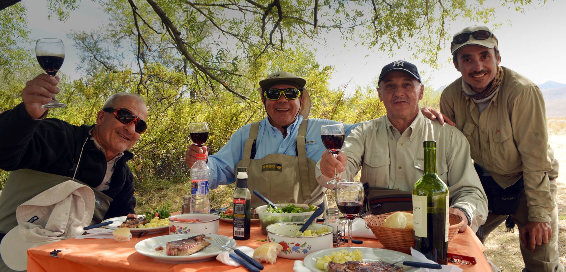 Fly fishing in Bariloche: Group of anglers enjoying a regional meal and a premium wine at their fishing camp after a day on the Limay River in Patagonia.